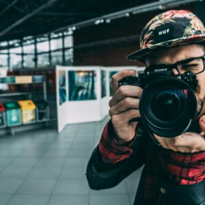 A young adult photographer with a DSLR camera indoors, highlighting modern photography.