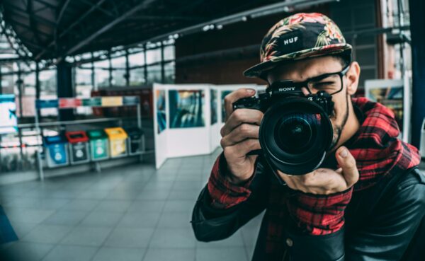 A young adult photographer with a DSLR camera indoors, highlighting modern photography.